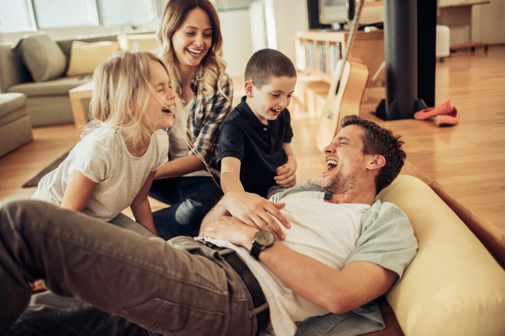 Das Foto zeigt eine junge Familie, die gemeinsam spielen