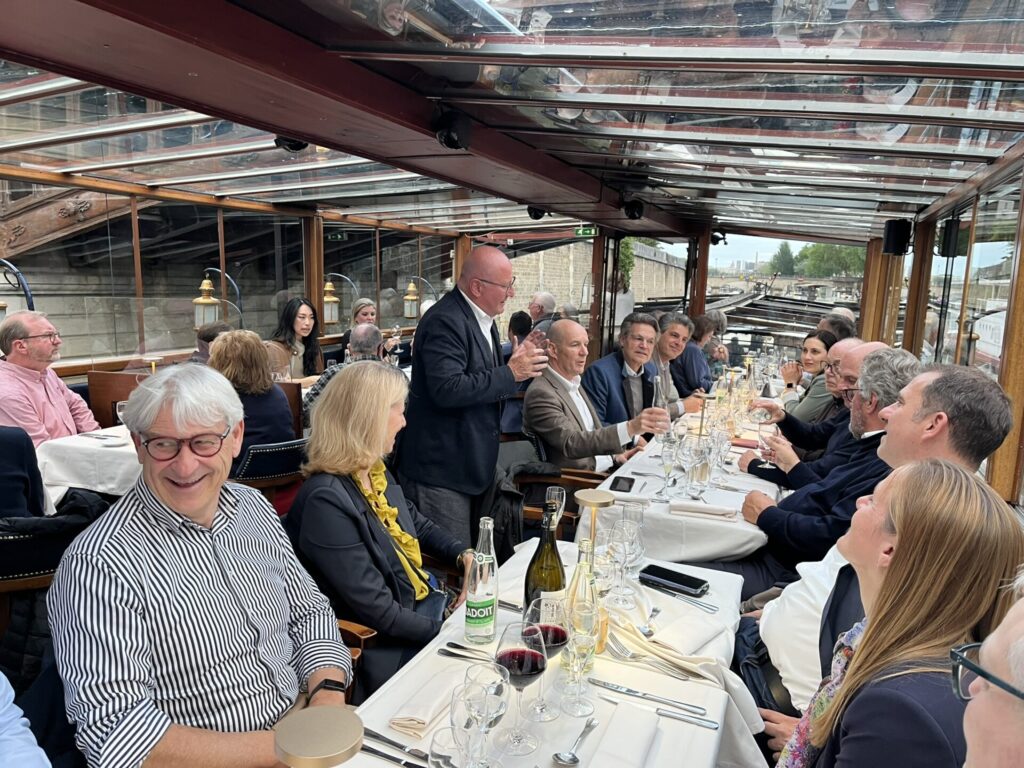 Das Foto zeigt unsere Delegation bei der abendlichen Schifffahrt auf der Seine (ich finde das Foto sehr schön, weil es durch den Vortrag von Frank Eloy so dynamisch wirkt, bin mir aber nicht sicher ob wir es verwenden können, weil hinten ja noch andere Personen drauf sind, die nicht zur Gruppe gehören)